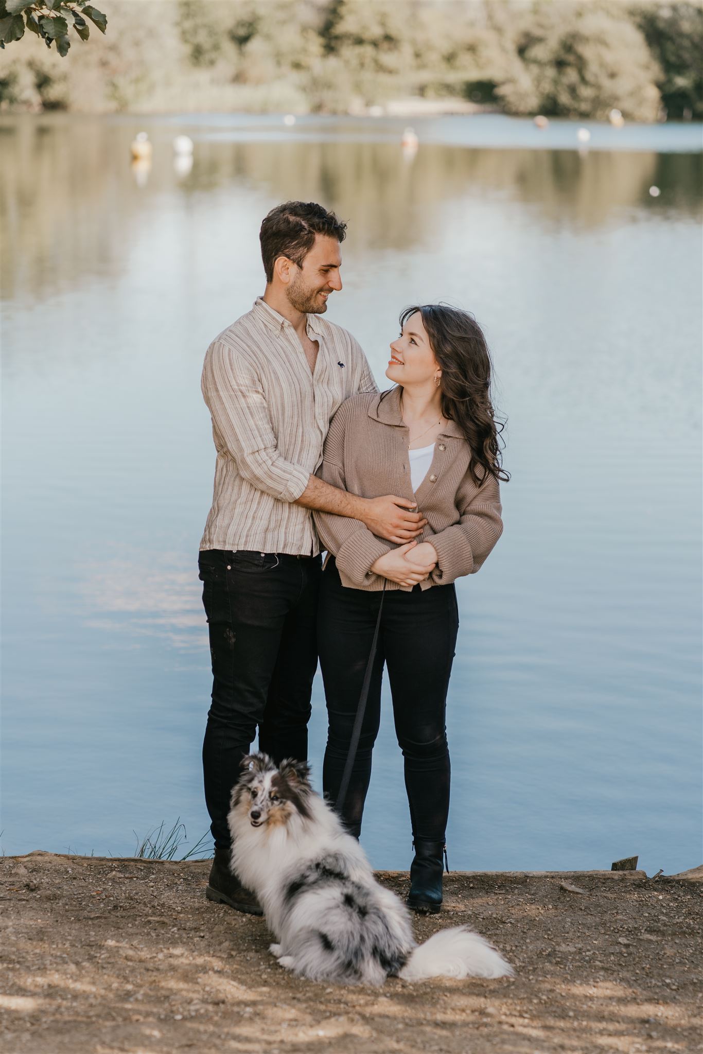 couple standing with their dog in front of a lake in kent couple shoot