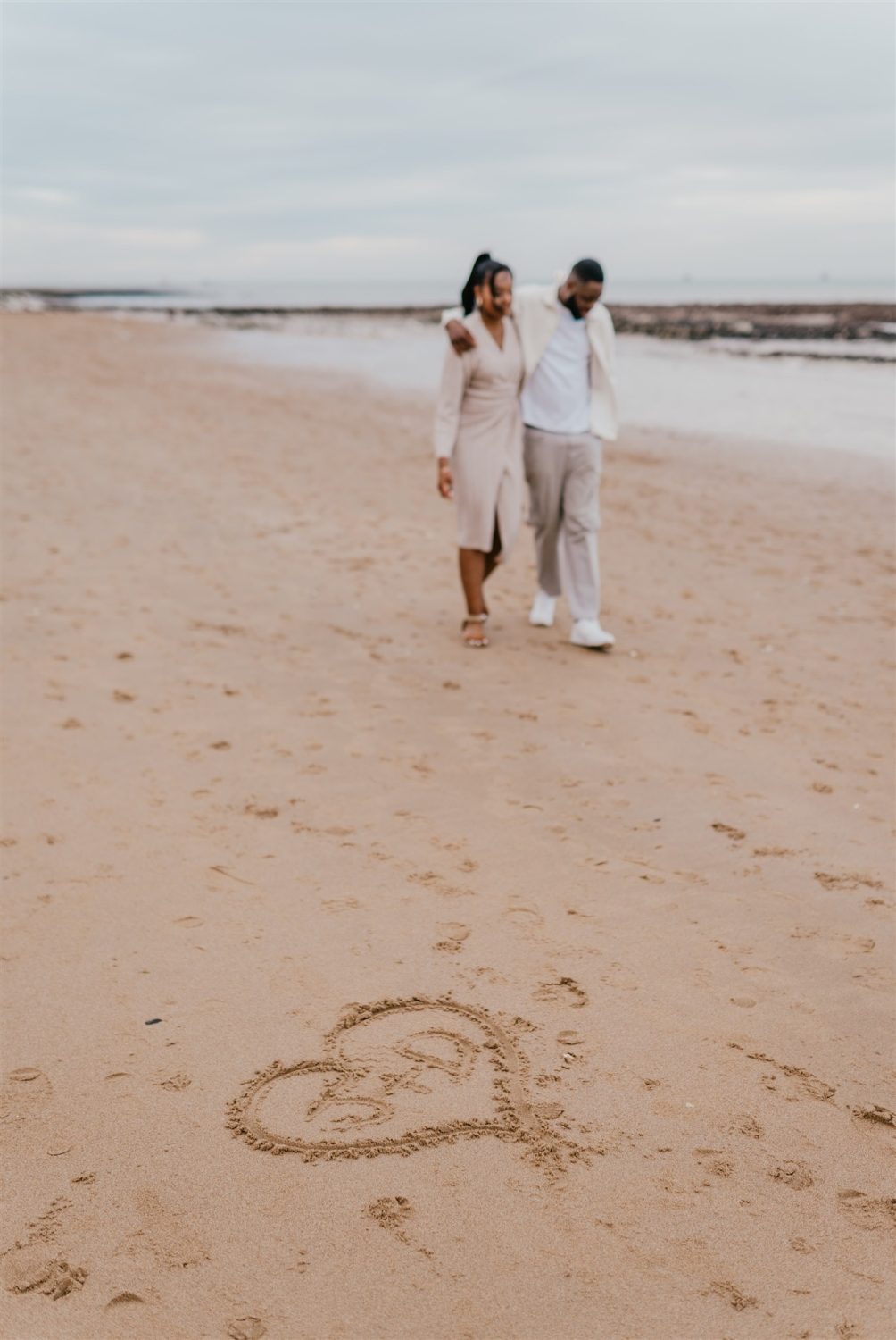 couple walk on the beach with heart drawn in the sand at botany bay couple shoot in kent