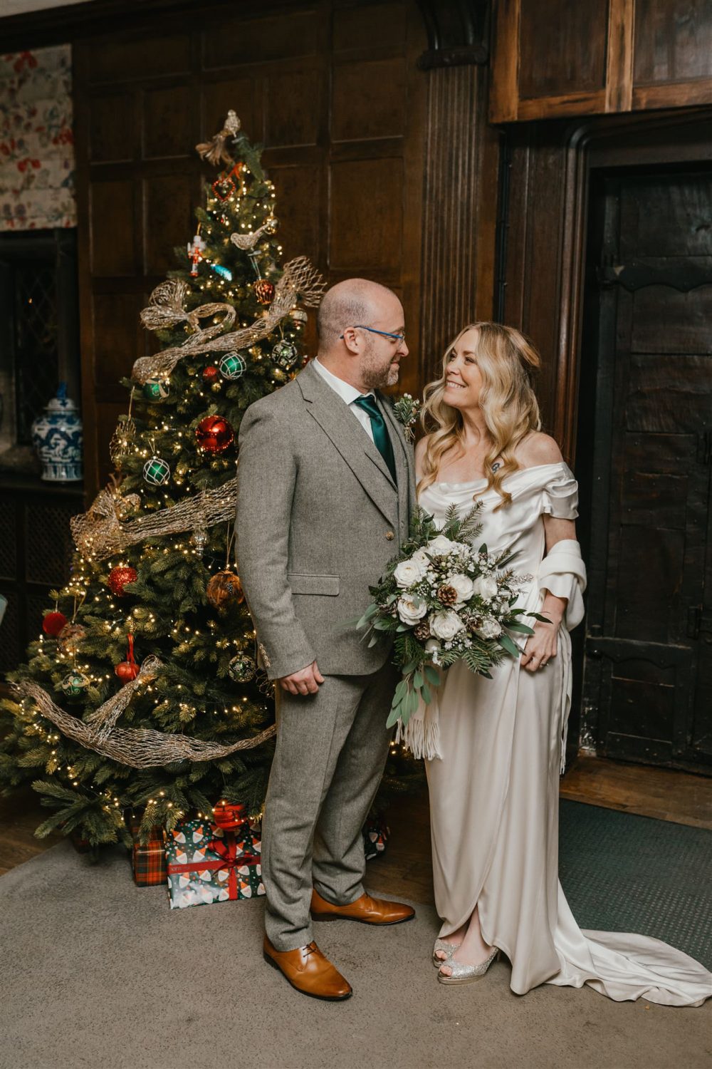 bride and groom in front of a christmas tree at winter wedding in surrey