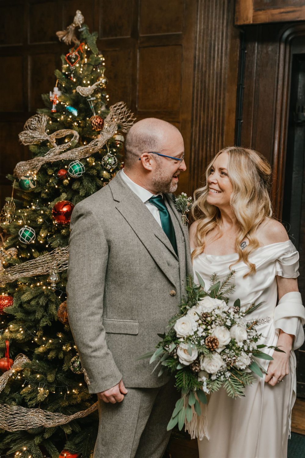 bride and groom in front of a christmas tree at winter wedding in surrey
