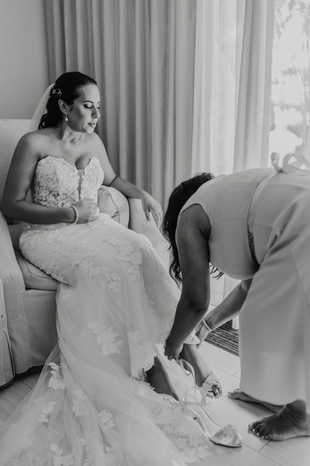 black and white photo of bride's mum helping her with shoes at destination wedding in the caribbean