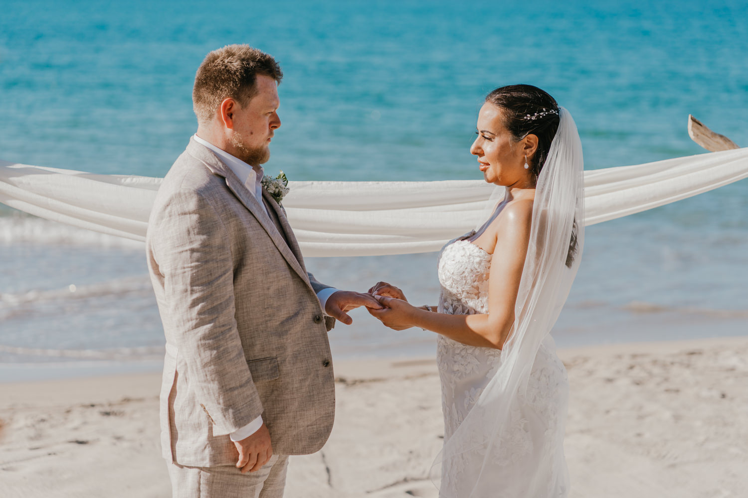 bride and groom exchange rings during beach wedding ceremony for saint lucia elopement at stolentime resort wedding venue in the caribbean