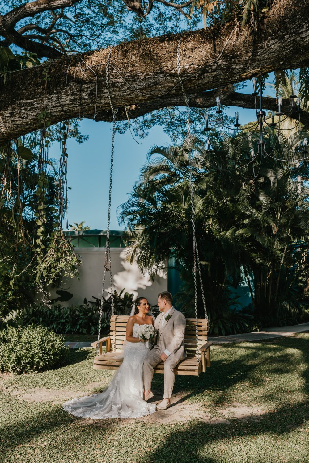 bride and groom sat on bench swing in the sun at stolentime resort saint lucia
