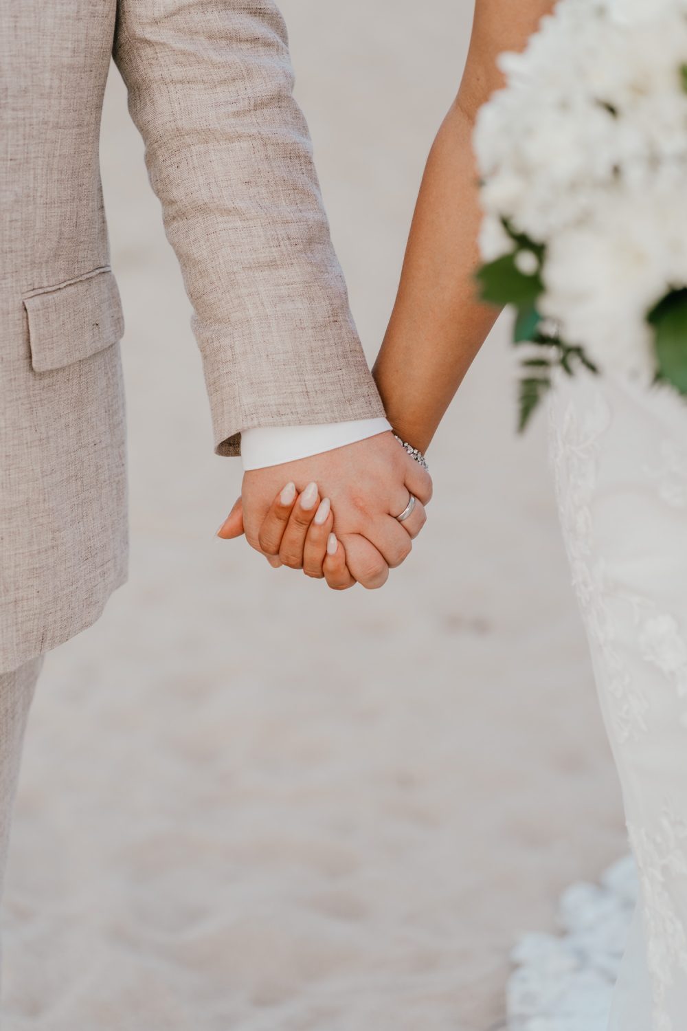 bride and groom hold hands on white sand beach at their saint lucia elopement