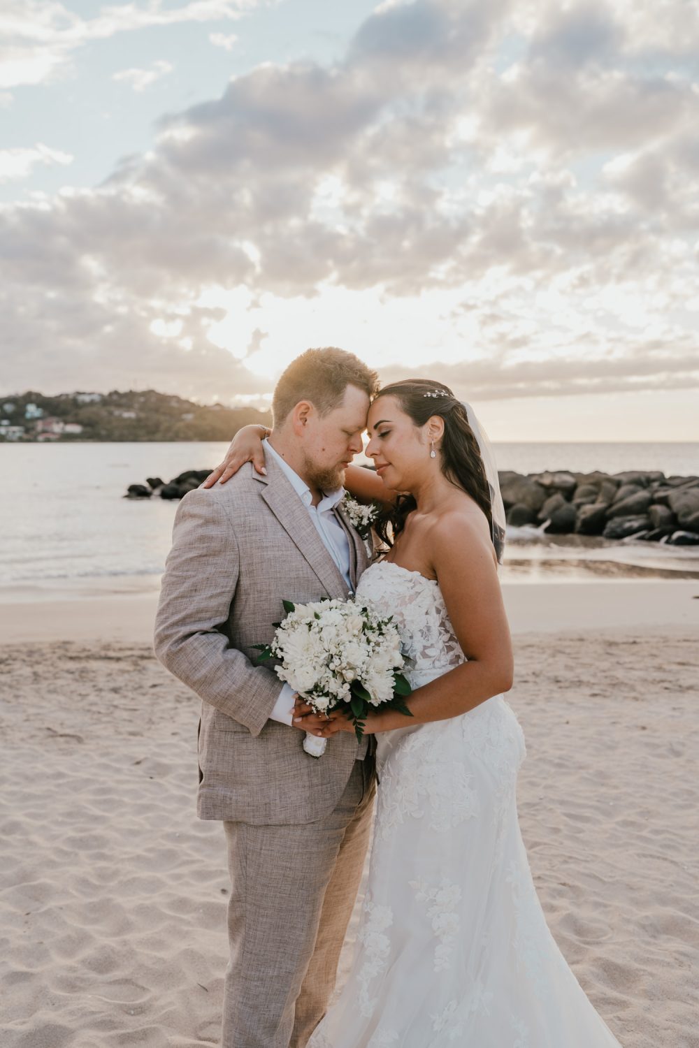 bride and groom stand together on the beach in saint lucia at sunset for golden hour couple portraits during their caribbean wedding