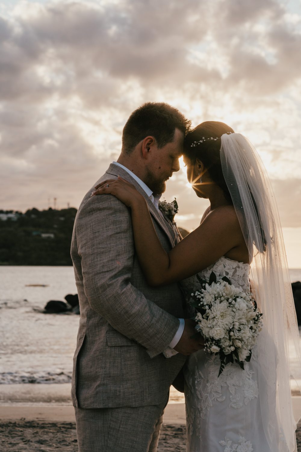 bride and groom stand together on the beach in saint lucia at sunset for golden hour couple portraits during their caribbean wedding