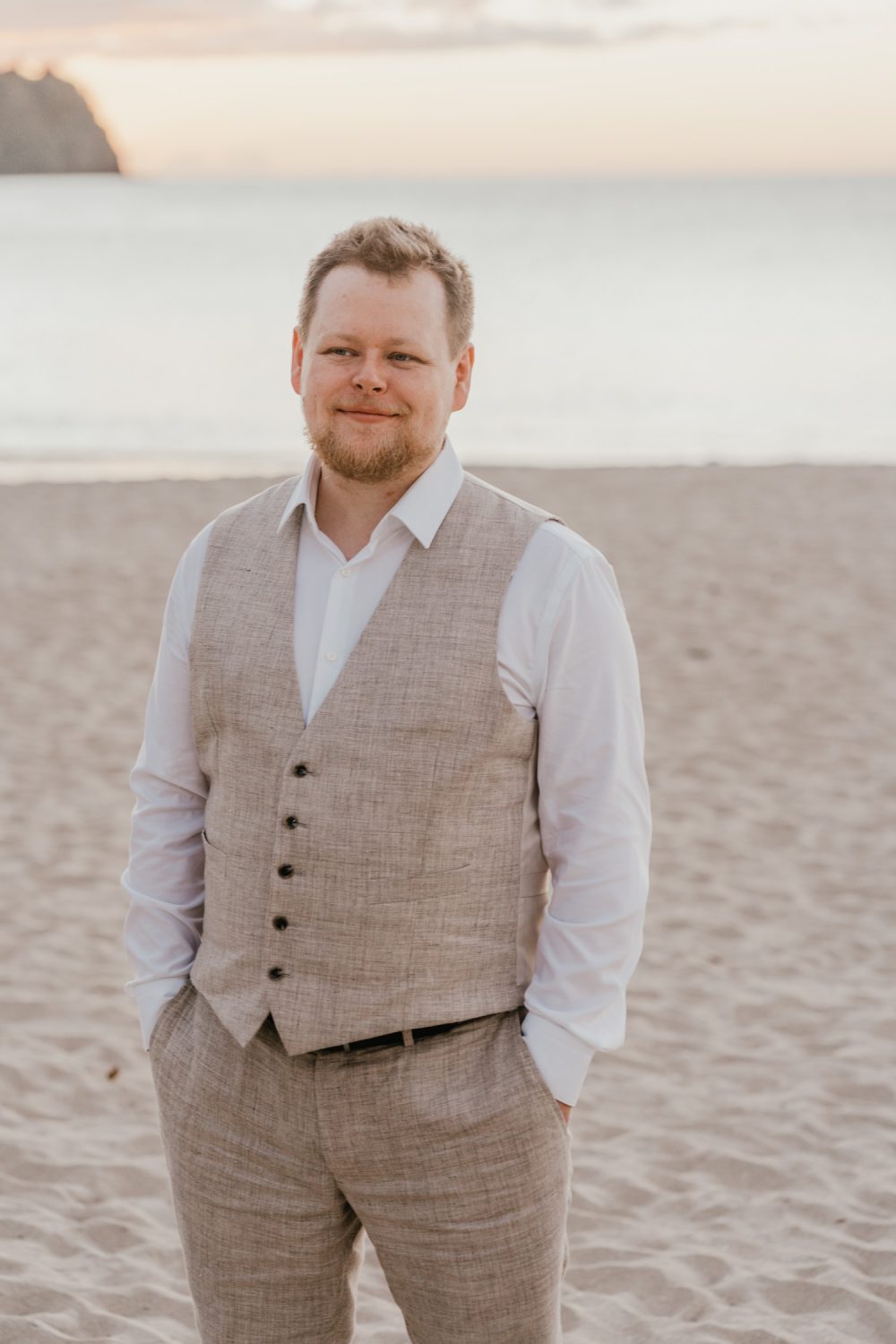groom stands on the beach in saint lucia in linen waistcoat