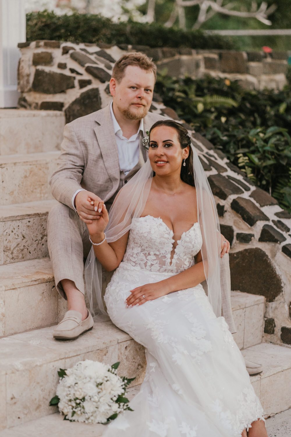 bride and groom sat on steps at stolentime resort wedding in saint lucia