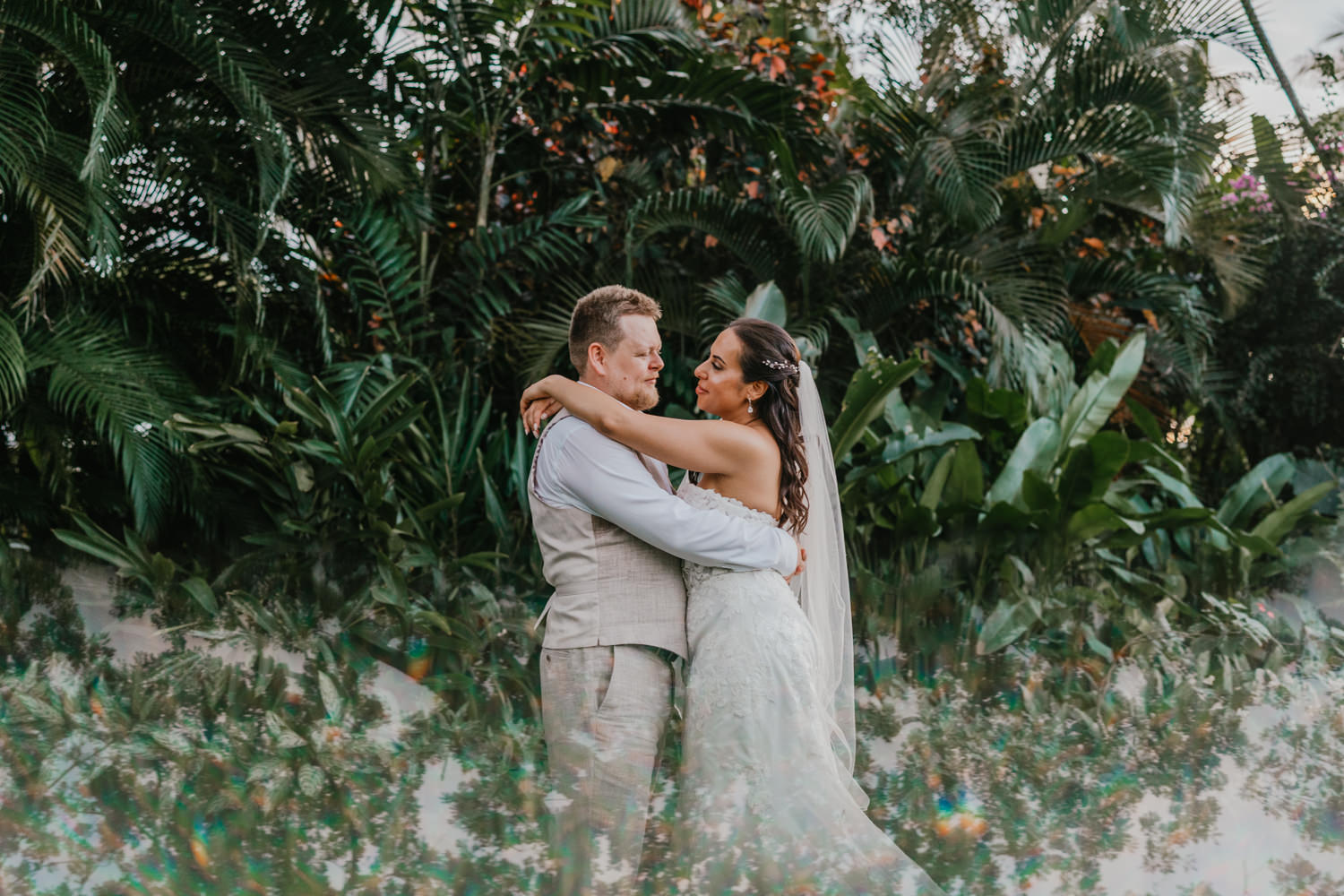 bride and groom surrounded by palm and banana trees with prism reflection effect