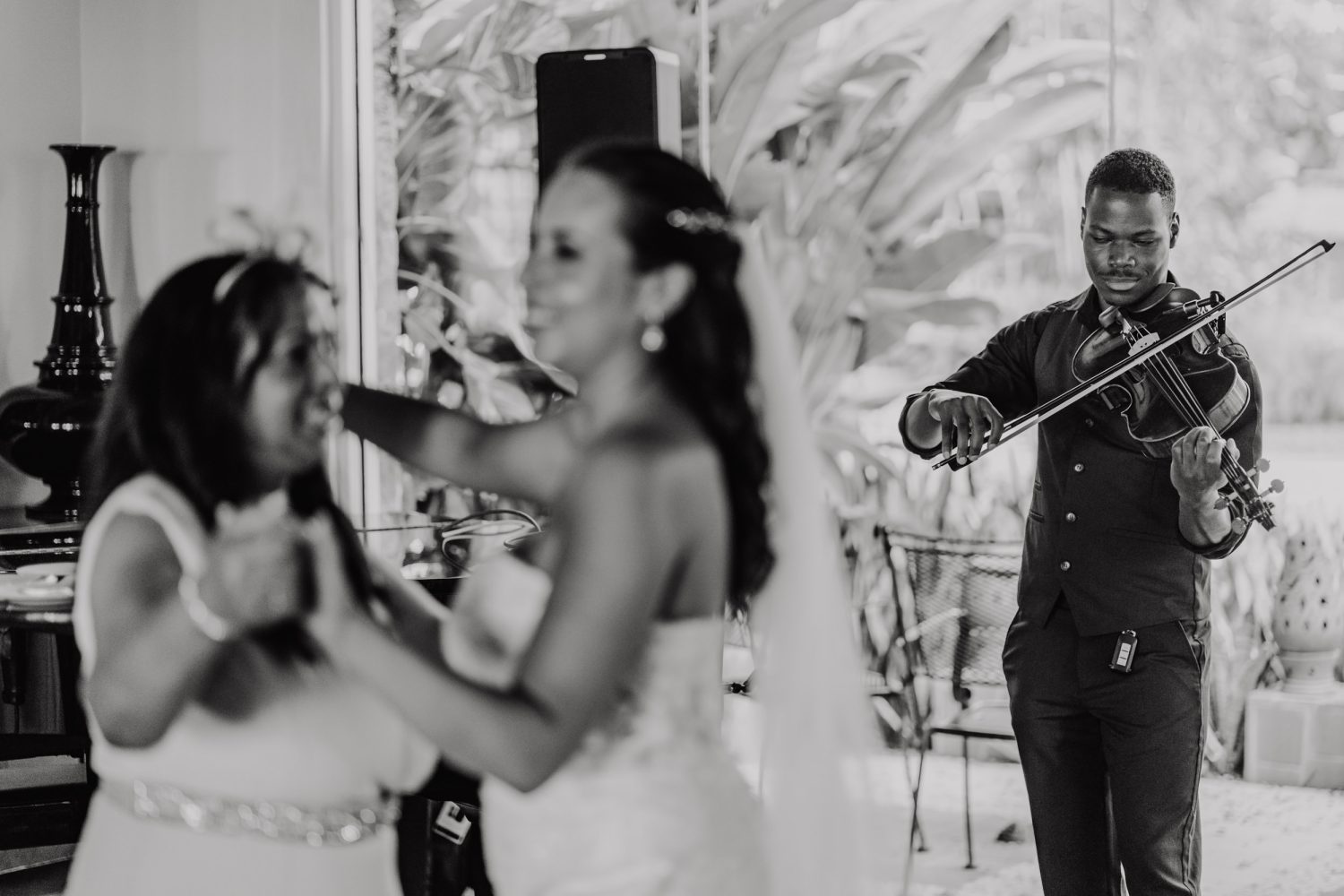 black and white image of violinist playing whilst bride and mum dance