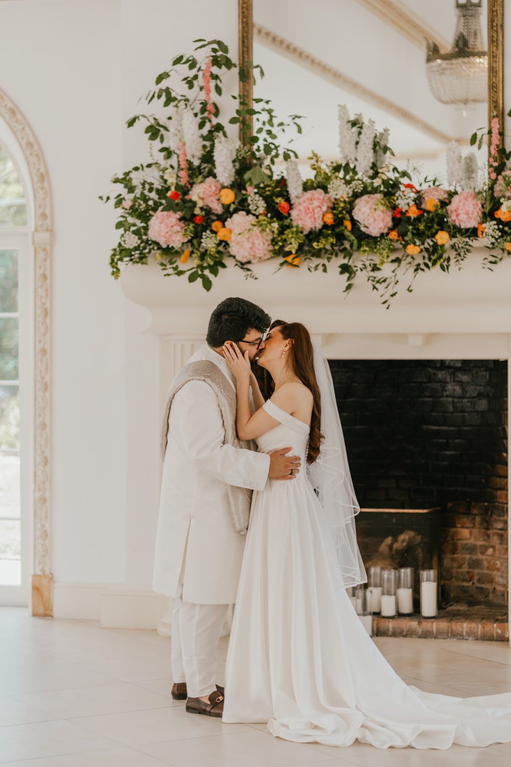 bride and groom kiss during first look in front of the fireplace at northbrook park wedding venue