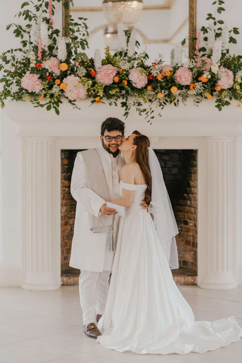 bride kisses groom on the cheek during first look at northbrook park wedding