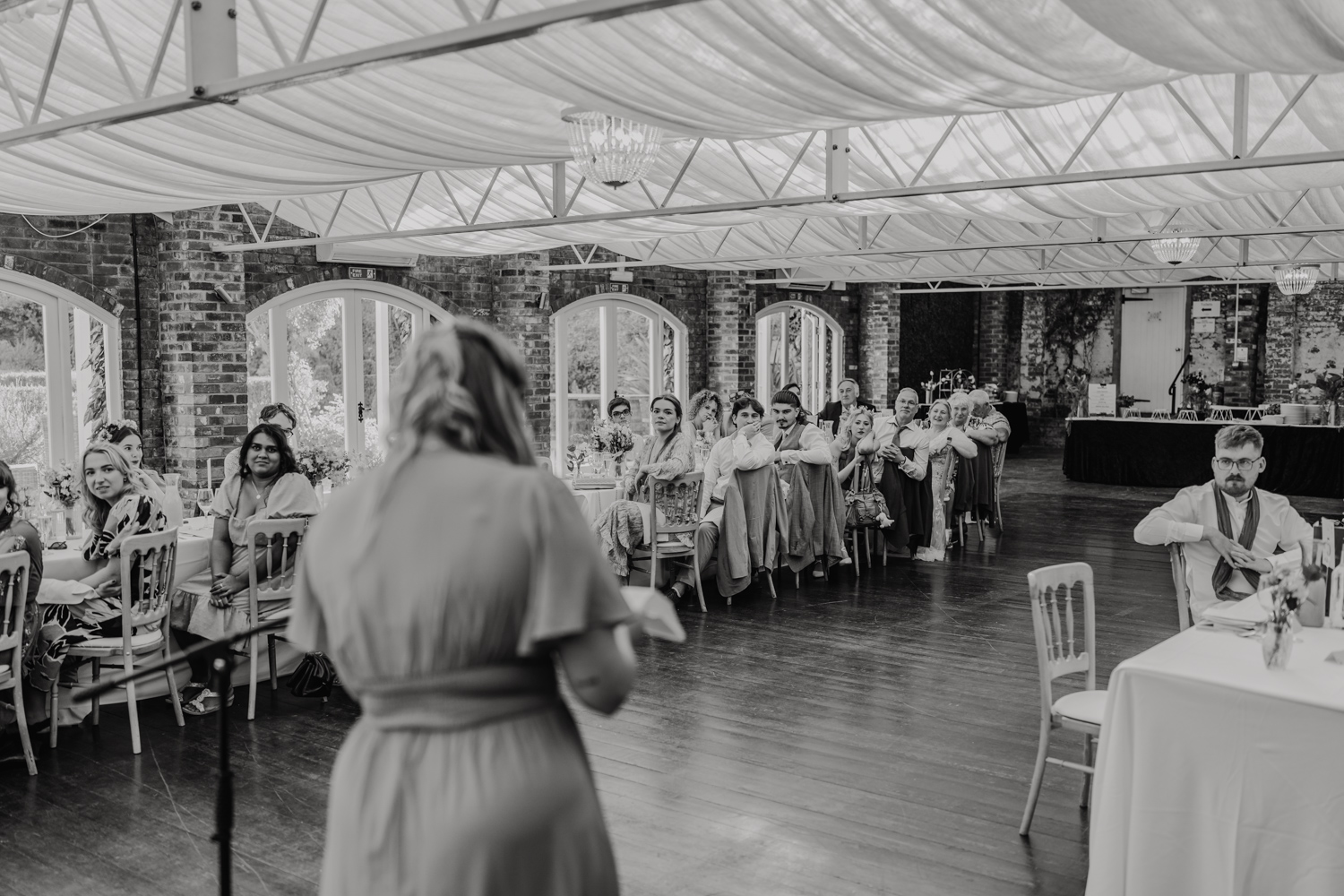 black and white photo of bridesmaid speech in front of guests at northbrook park wedding