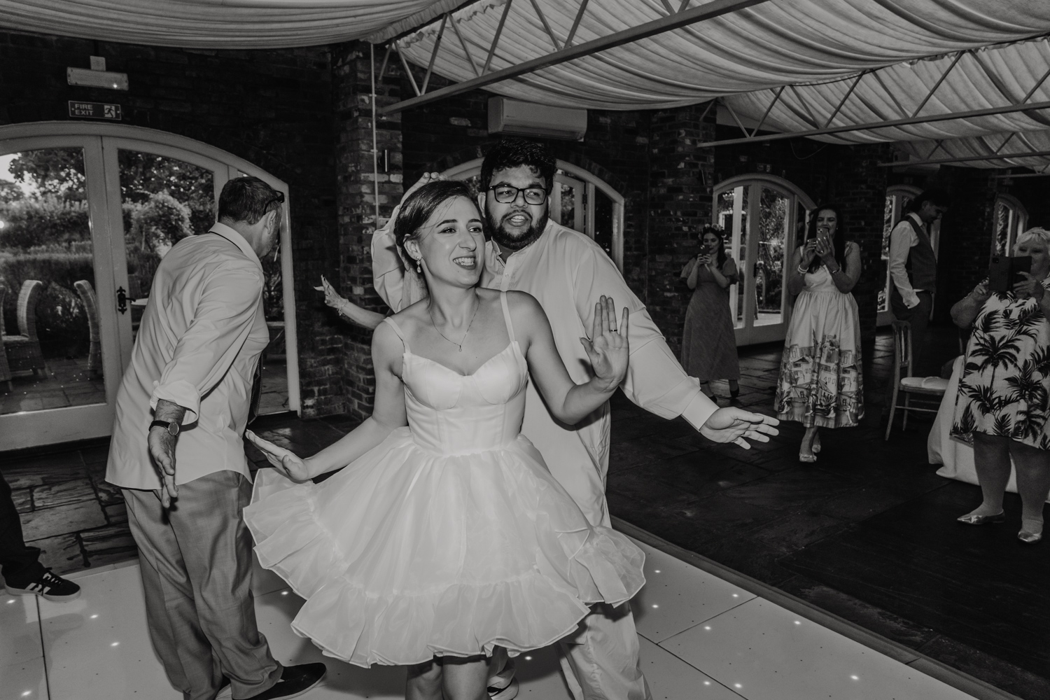 black and white photo of bride and groom dancing together on wedding day