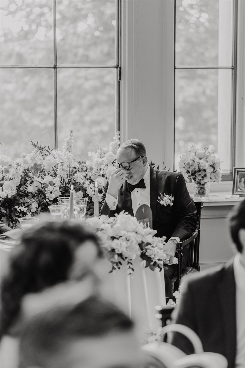black and white photo of groom's reaction to speeches in the library at trinity house wedding venue in london