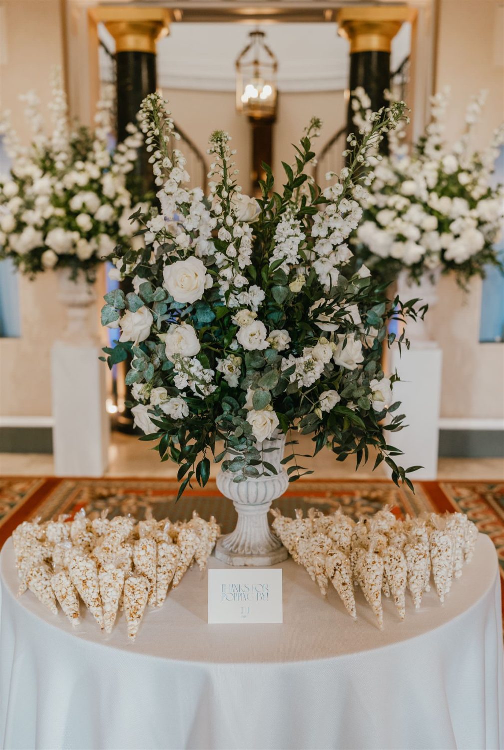 popcorn wedding favours on a table with flower urn and sign that reads thanks for popping by