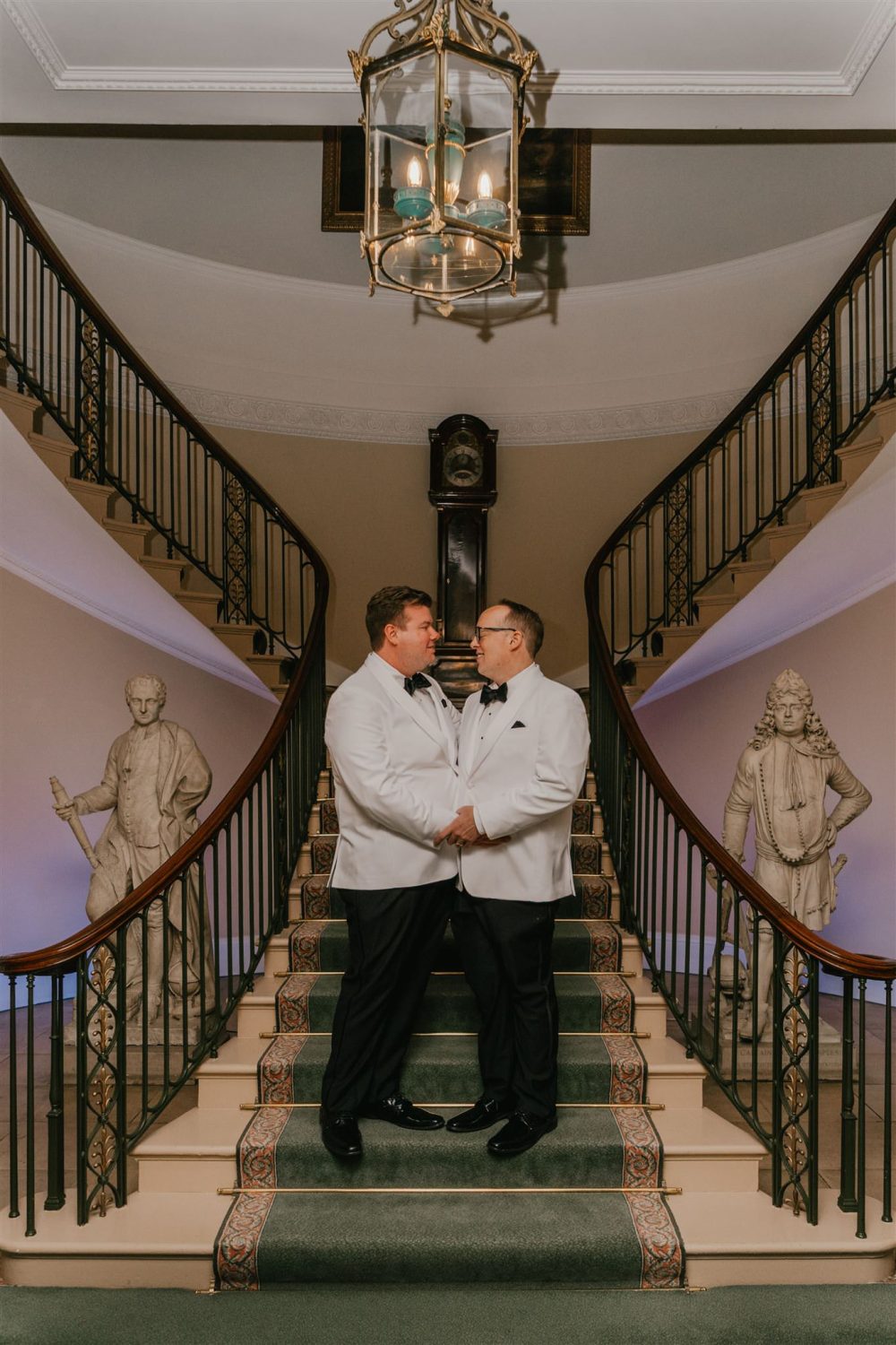 grooms portraits with white tux jackets on the staircase at trinity house in london