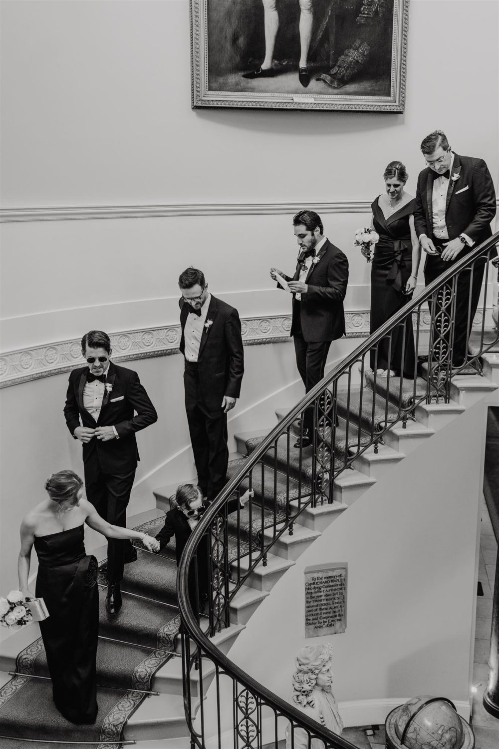 black and white photo of wedding party descending staircase at trinity house london wedding