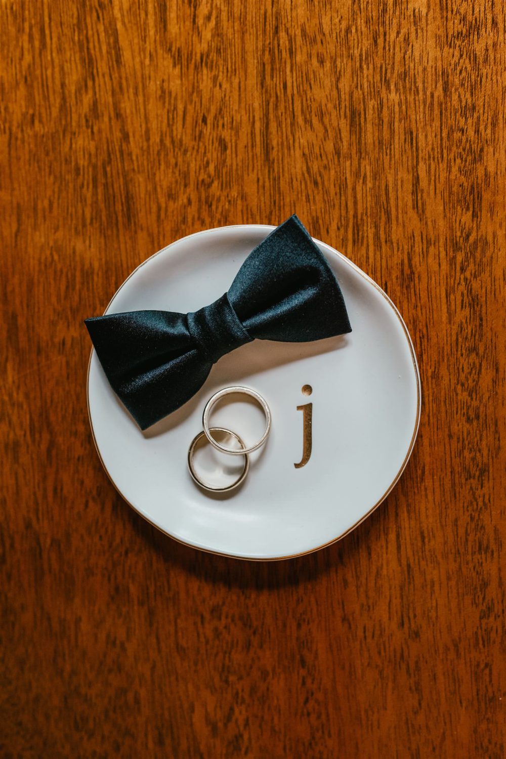 groom's bowtie with wedding rings on a dish