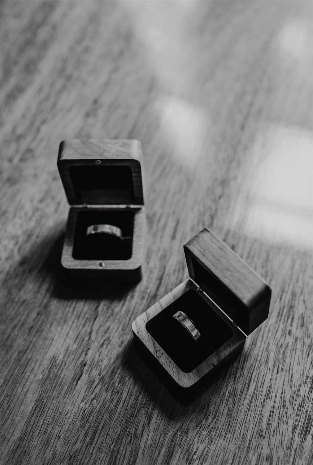 black and white image of wedding rings in wooden boxes