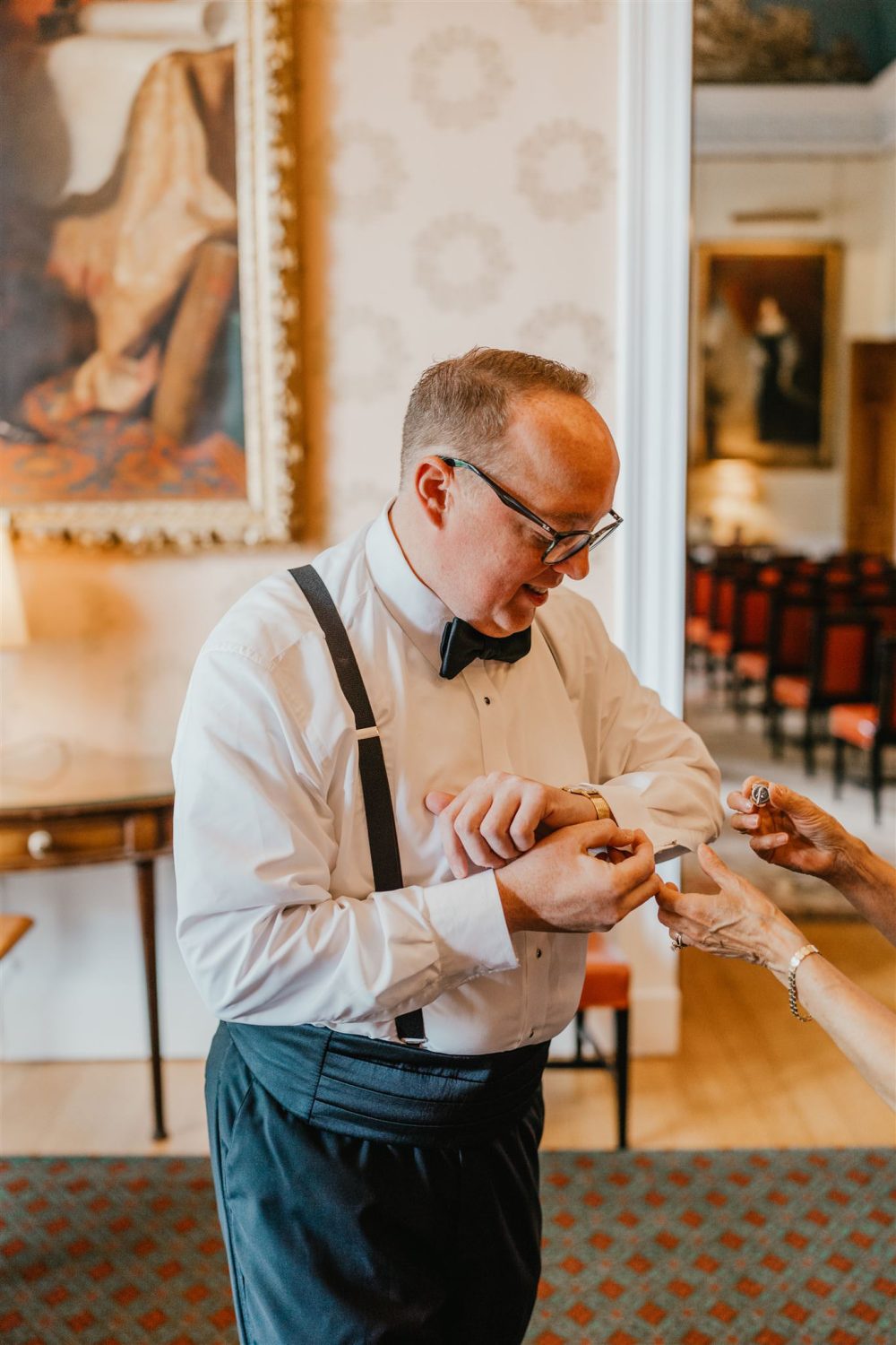 groom putting on cufflinks before trinity house wedding in london