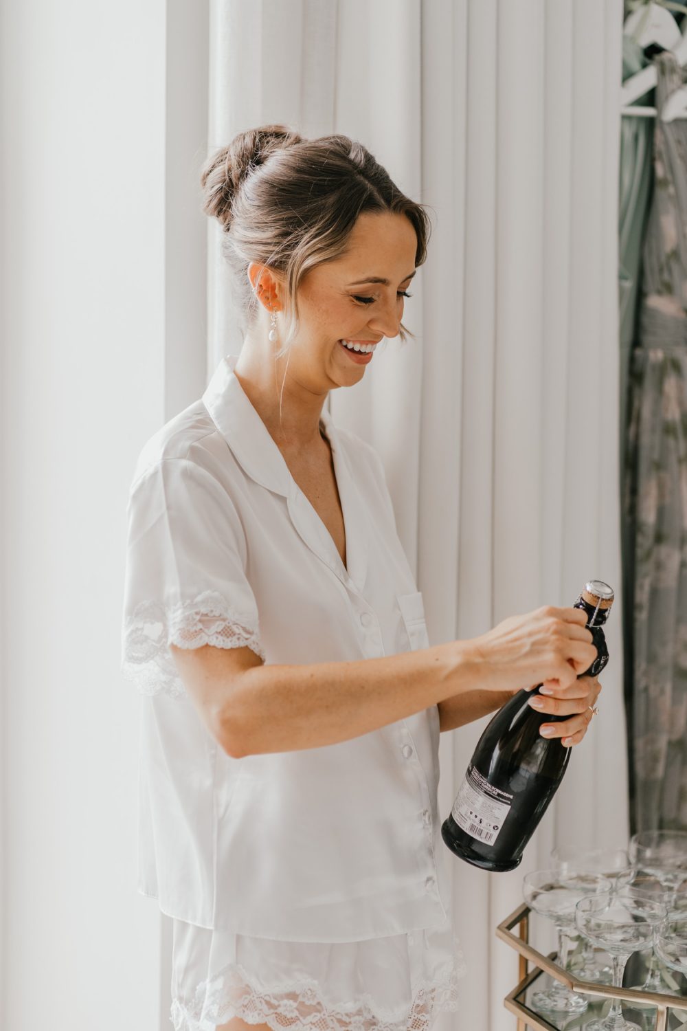 bride opening champagne on wedding morning