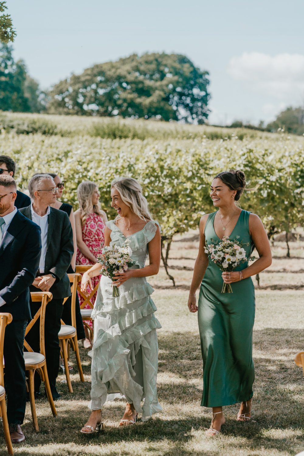 bridesmaids walk down the aisle at vineyard wedding ceremony at English Oak Vineyard