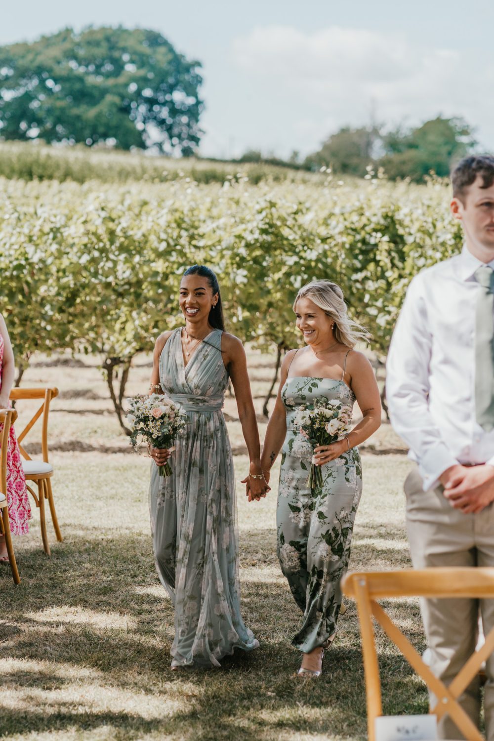 bridesmaids walk down the aisle at vineyard wedding ceremony at English Oak Vineyard