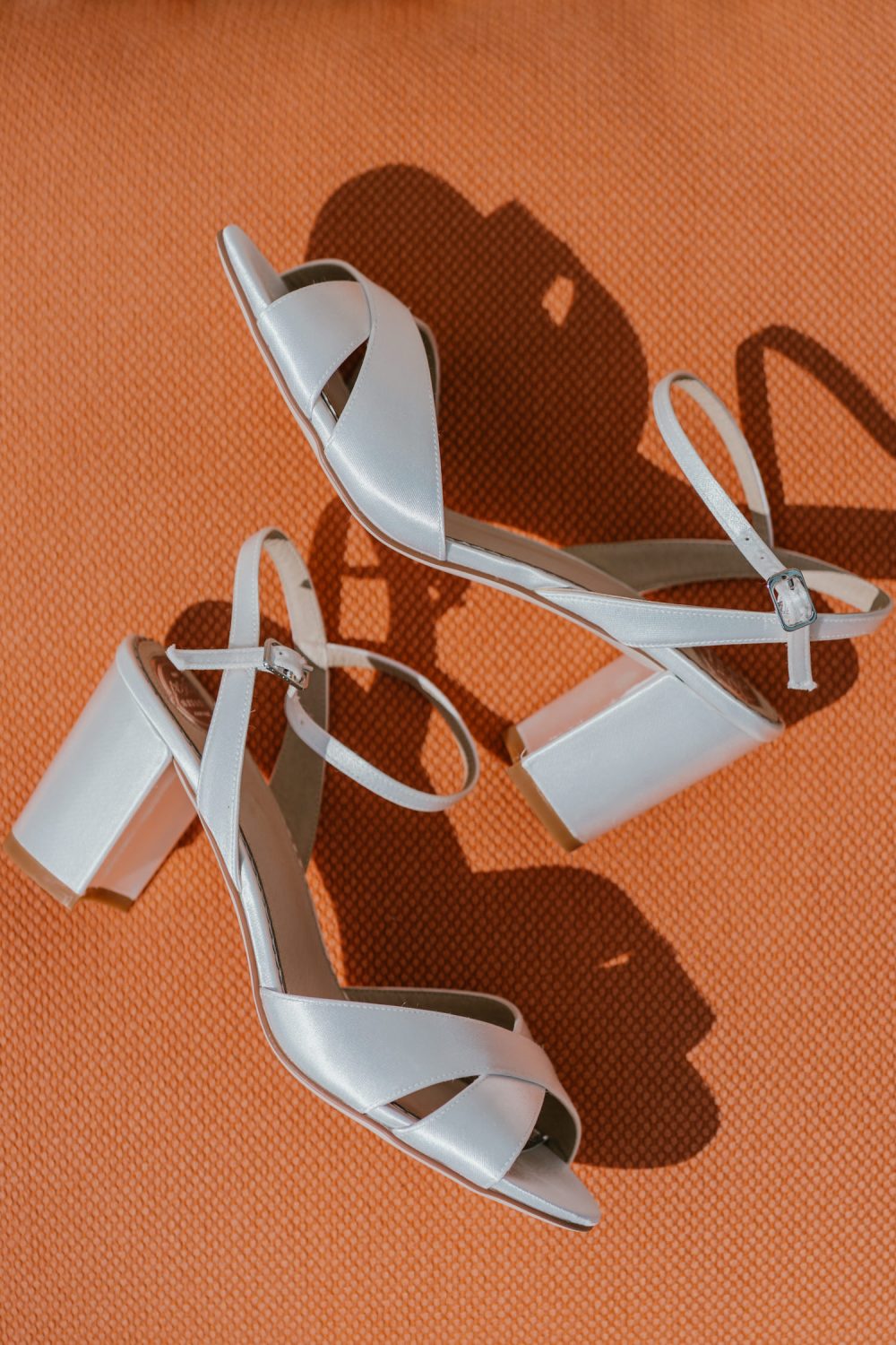 wedding shoes laying on an orange cushion in the sun