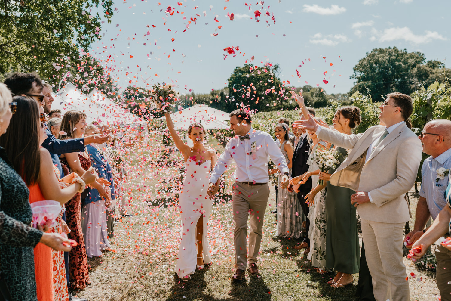 bride and groom walk through confetti tunnel at vineyard wedding ceremony at English Oak Vineyard