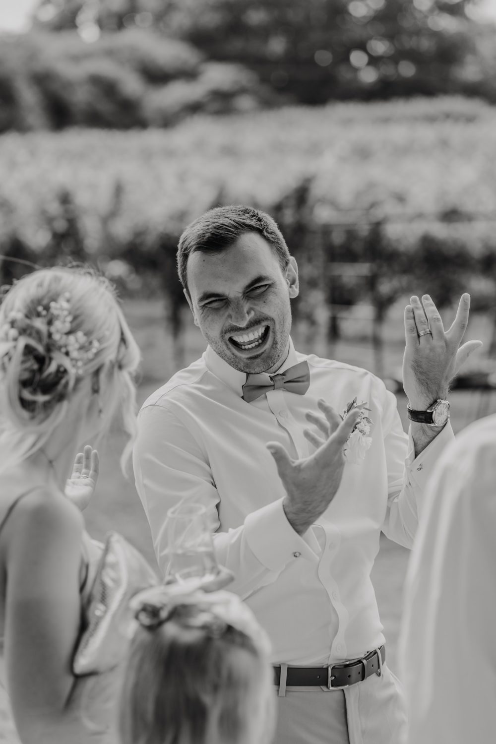 black and white photo of groom during drinks reception at English Oak Vineyard wedding in dorset