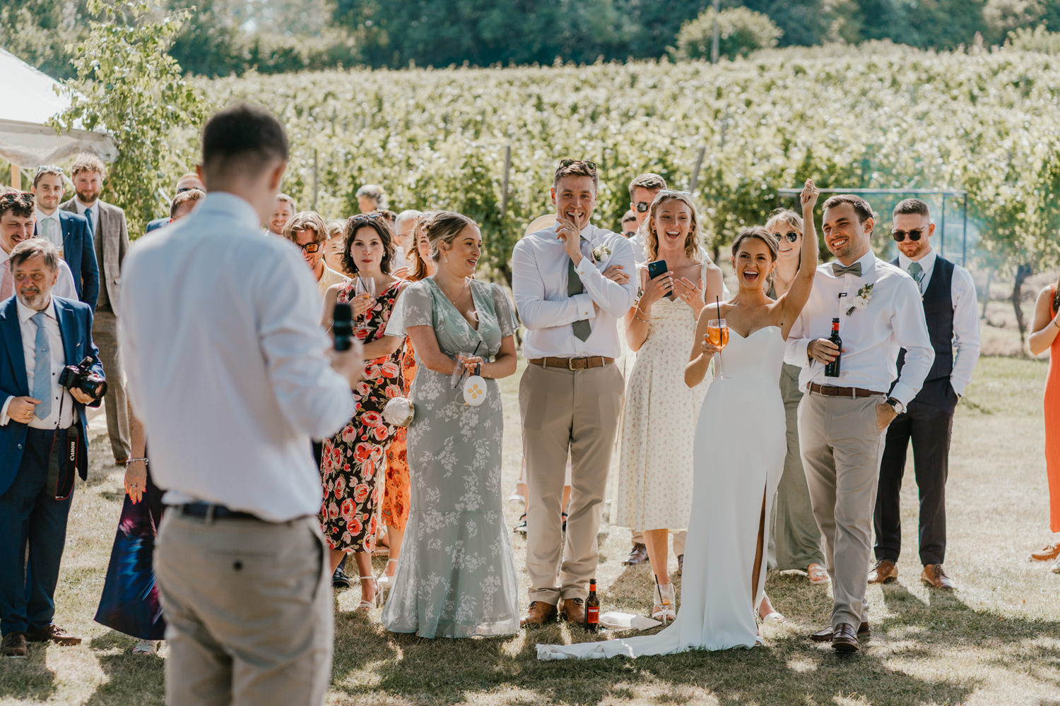 bride cheers during outdoor speeches at English Oak Vineyard wedding in dorset