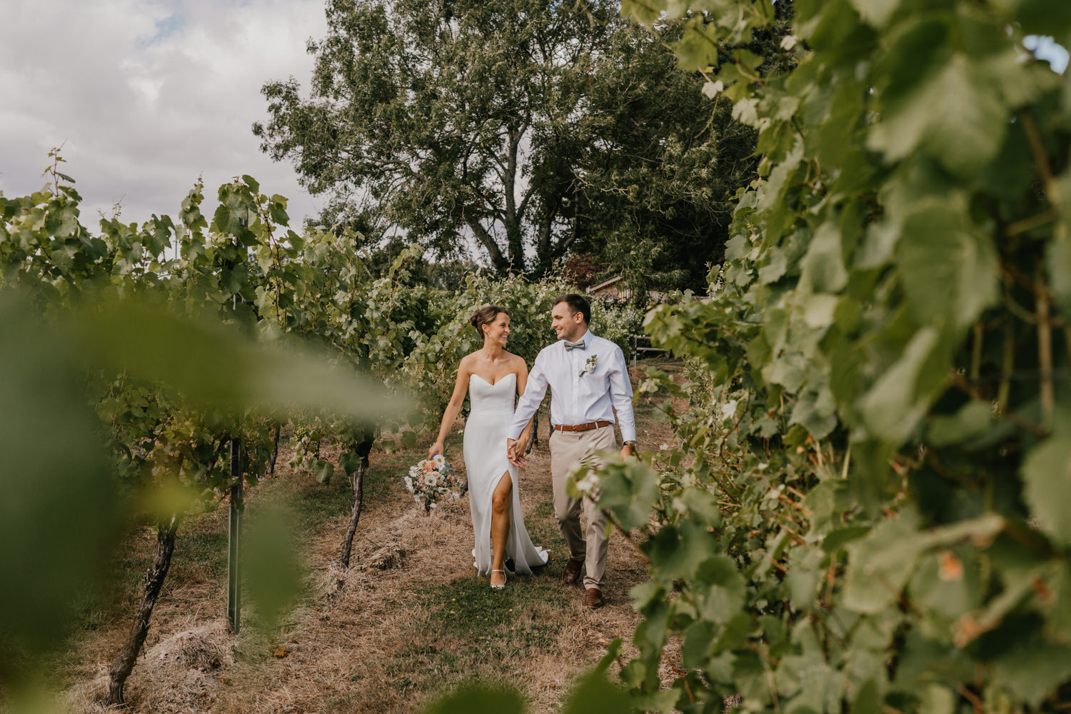 bride and groom walk through vines at English Oak Vineyard wedding in dorset