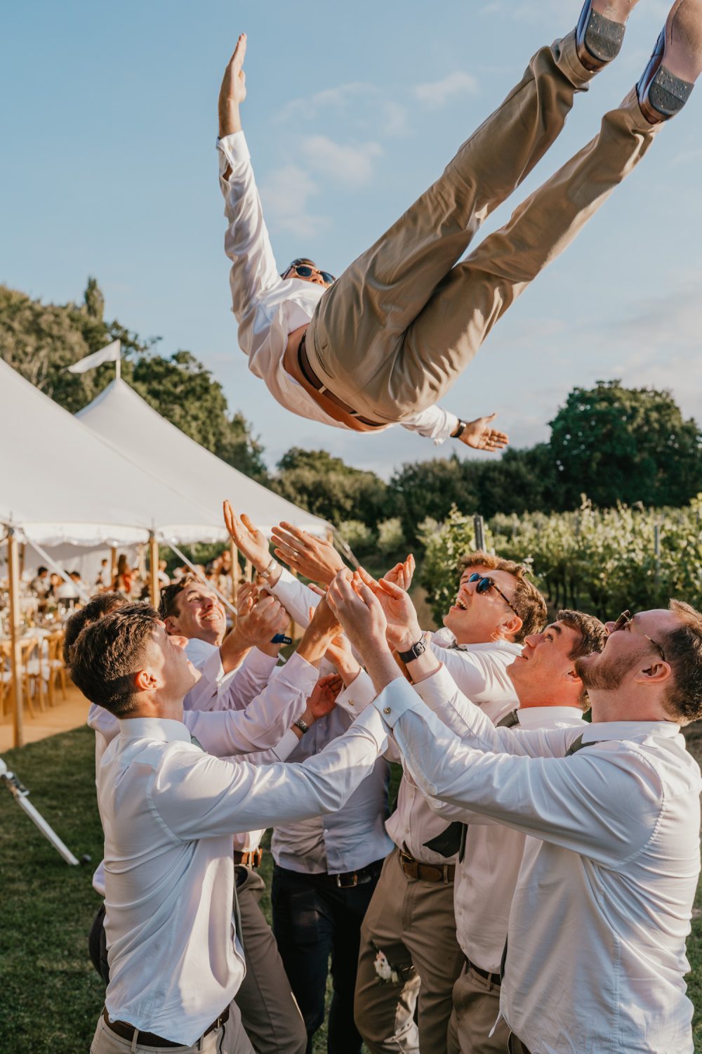 groomsmen throw the groom up in the air