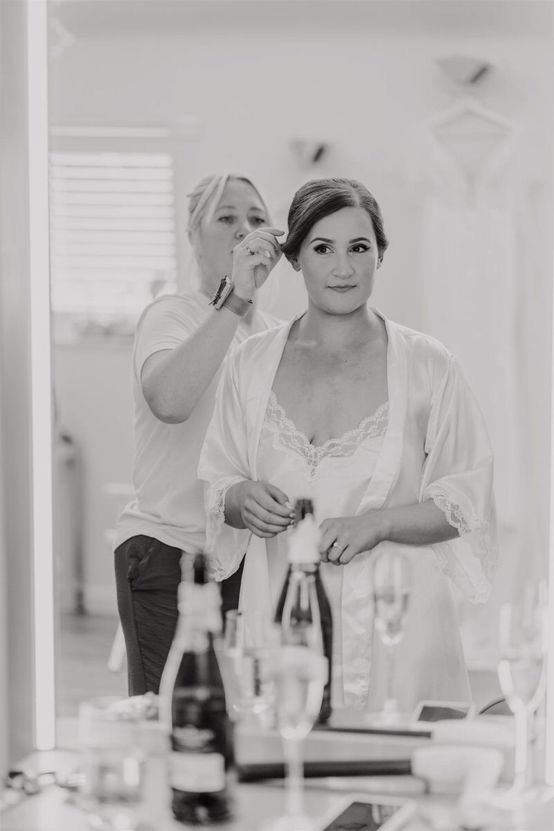 black and white image of bride having her hair done in preparation suite at winters barns canterbury