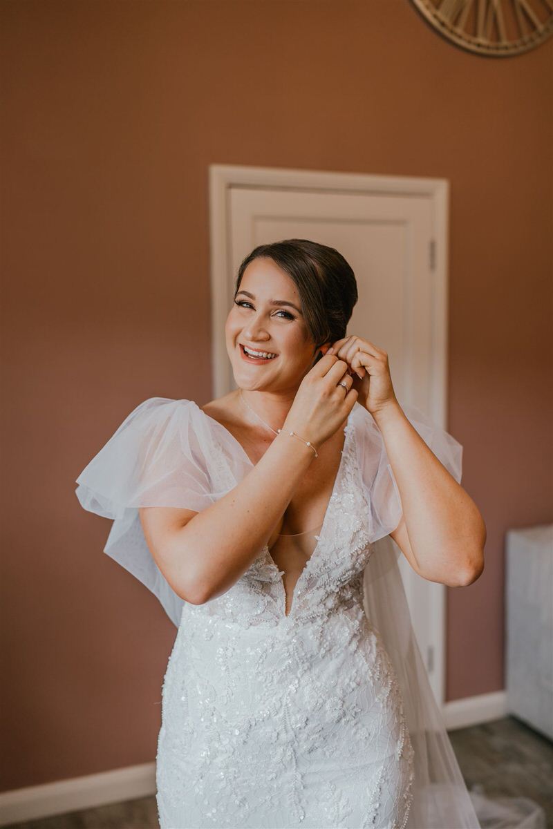 bride puts on earrings on her wedding morning at winters barns in canterbury
