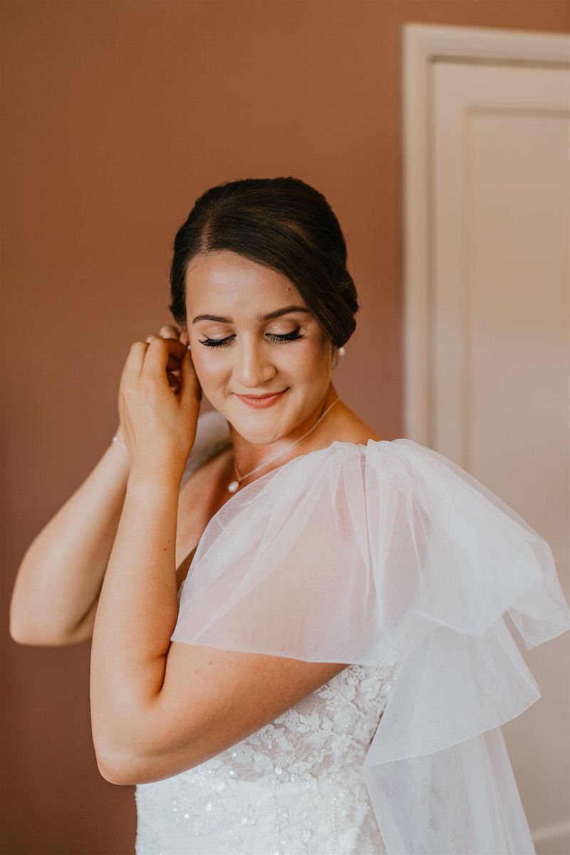 bride puts on earrings on her wedding morning at winters barns in canterbury