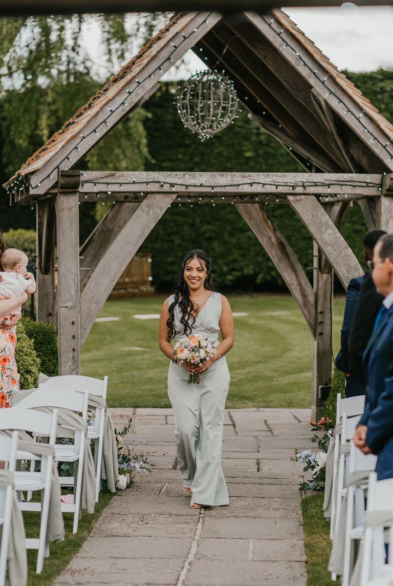 bridesmaid walking down the aisle during outdoor ceremony at winters barns wedding