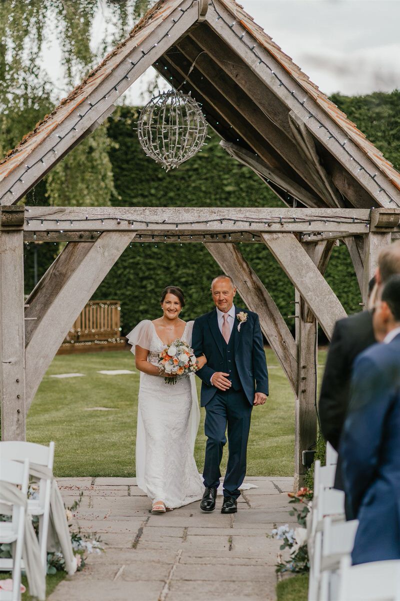 bride walks down the aisle with her father at outdoor winters barns wedding