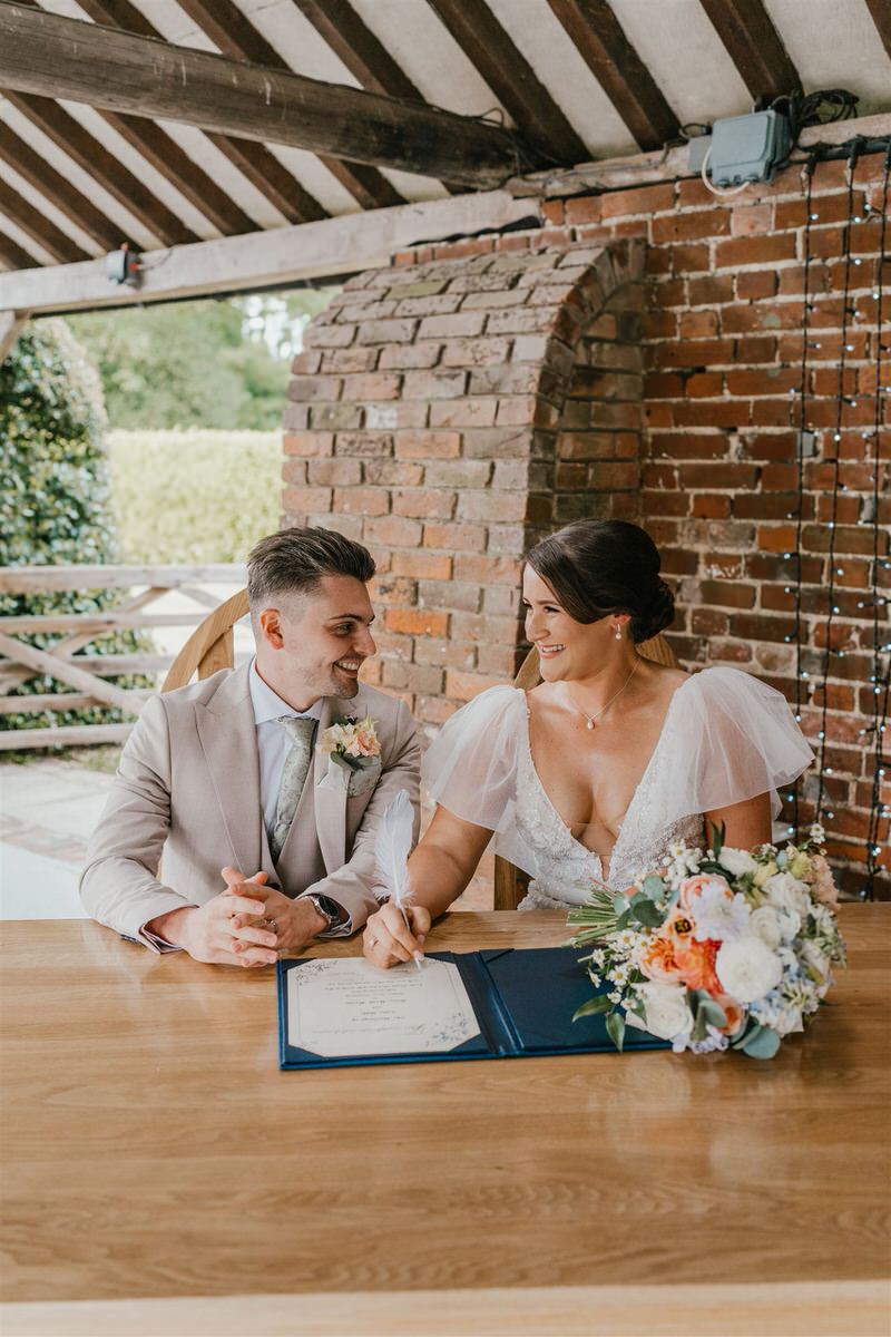 bride and groom sign register during outdoor winters barns wedding ceremony