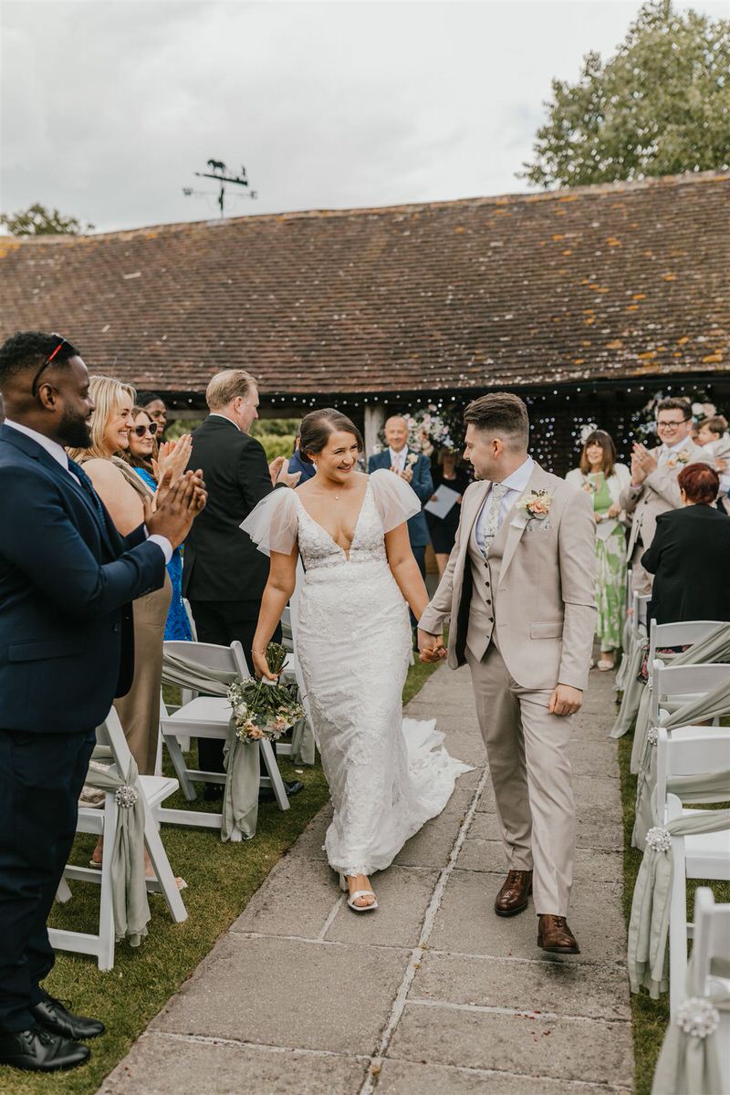 bride and groom walk back up the aisle after outdoor winters barns wedding ceremony