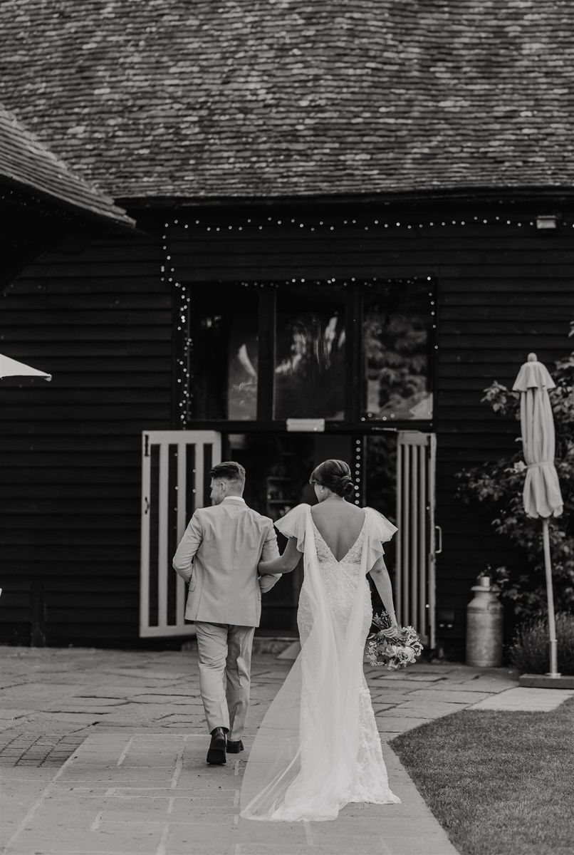 black and white image of bride and groom walking at winters barns wedding venue in canterbury