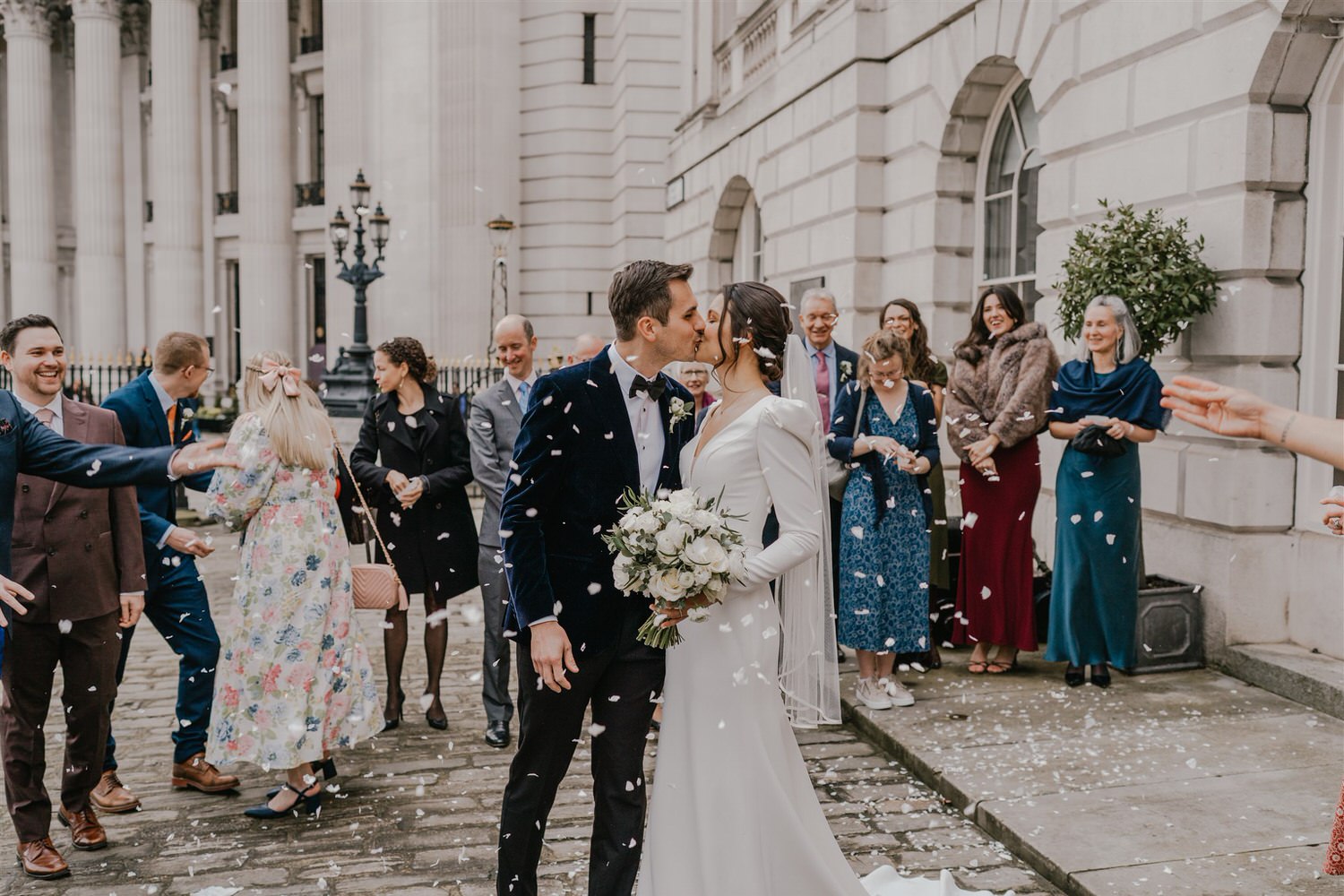 bride and groom kiss during confetti tunnel outside trinity house winter wedding in london