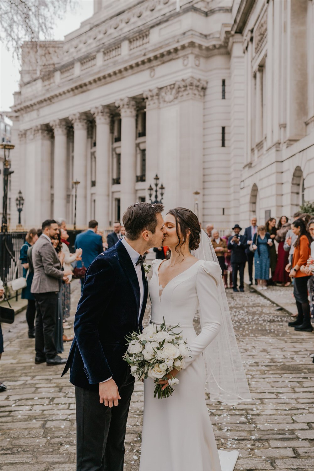 bride and groom kiss after confetti tunnel outside trinity house winter wedding in london