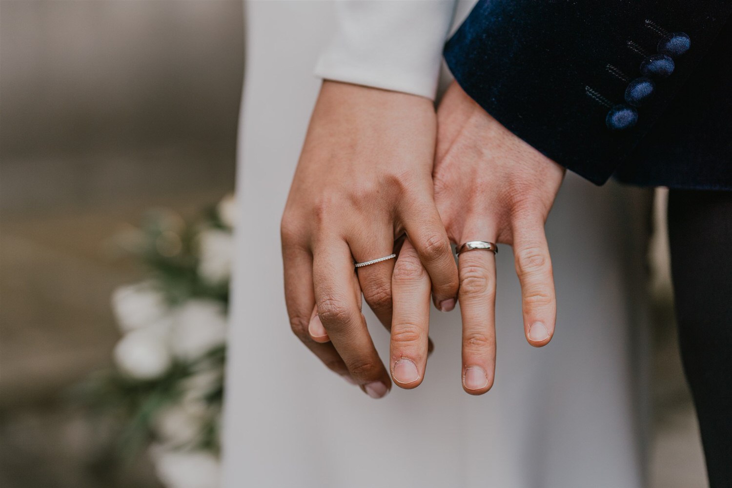 bride and groom hold hands with wedding rings